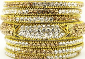 Stack of shining gold bangles with detailed patterns reflecting light beautifully.