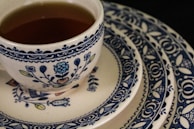 Close-up of blue ceramic mugs with delicate patterns stacked beside matching plates.