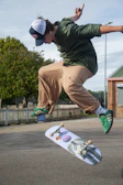 Skater mid-trick wearing stayd1fferent branded cap and jeans