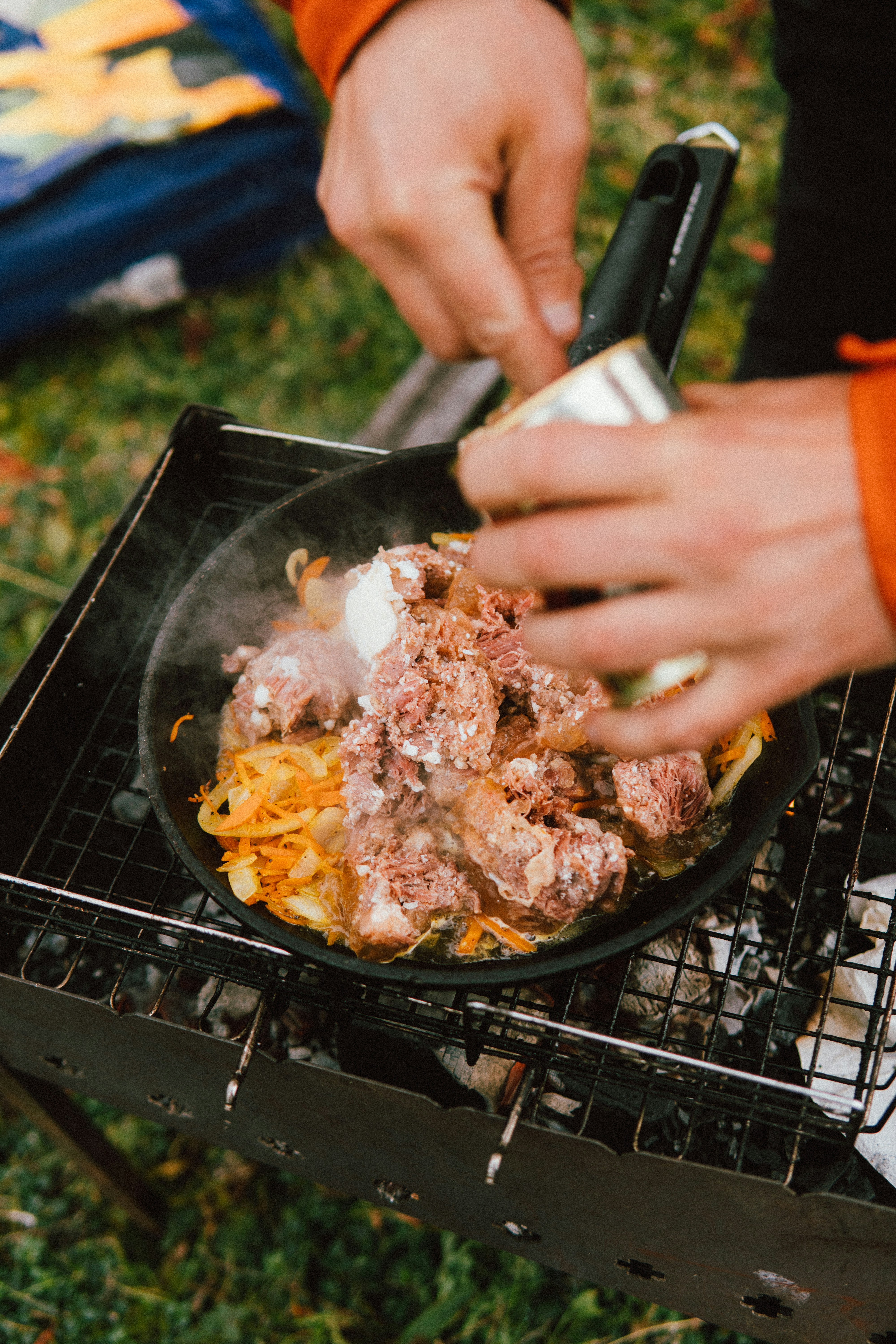 a person holding a knife over a grill with food