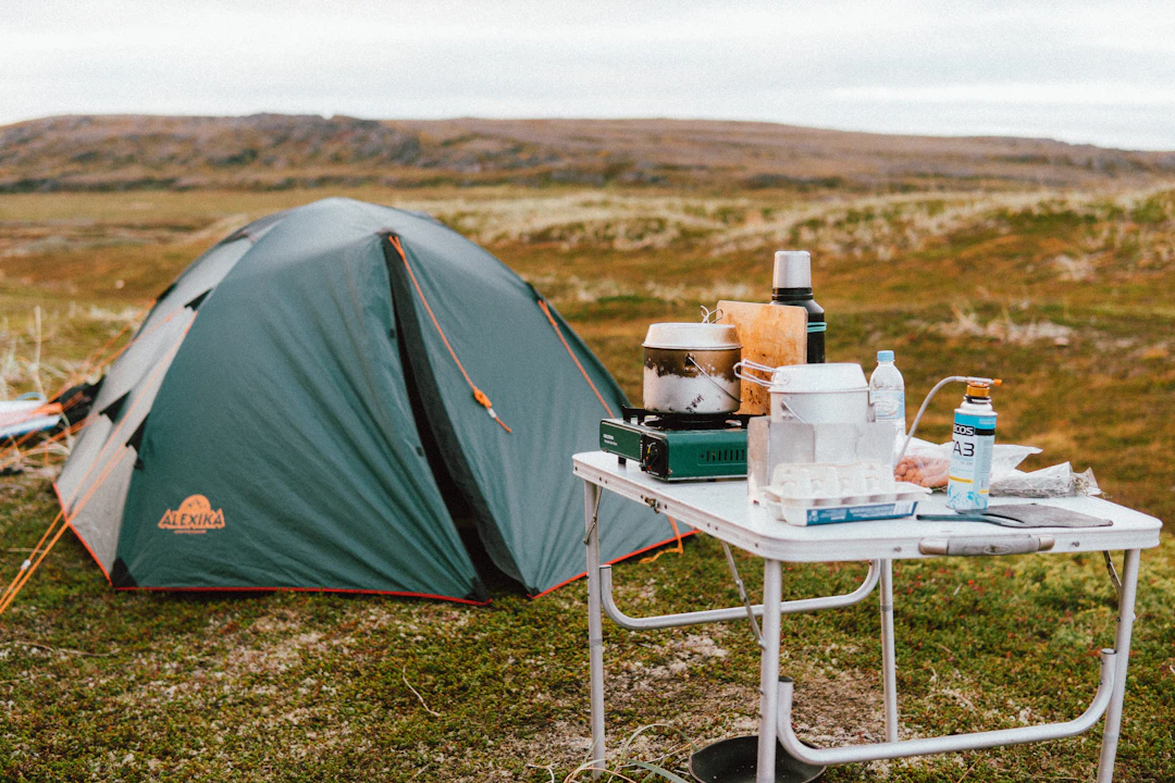 Camping table set with a frying pan, food and cookware beside a tent