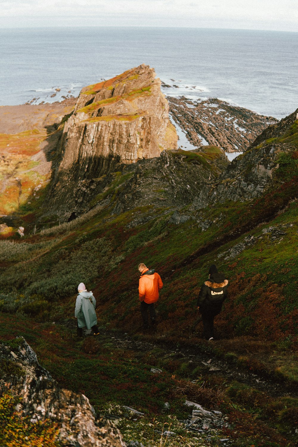 a group of people standing on a rocky cliff overlooking the ocean