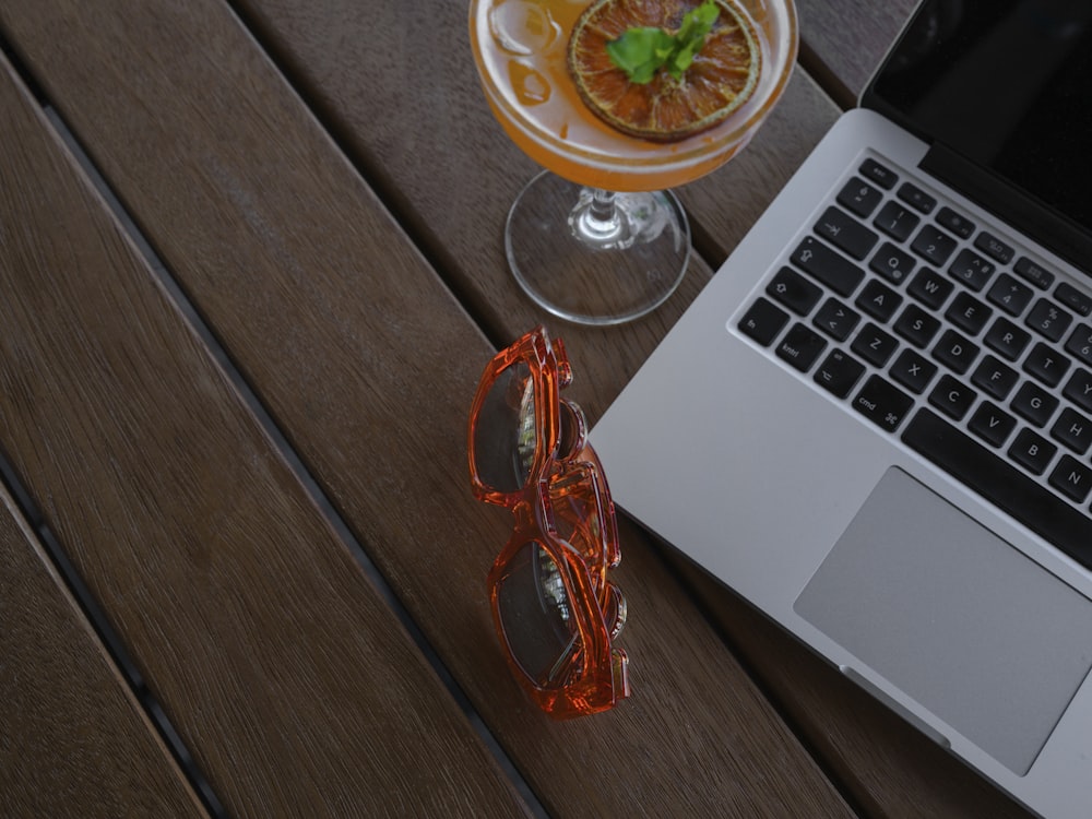 a glass of liquid next to a laptop