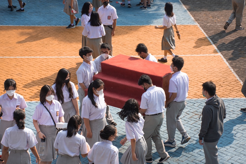 a group of people standing around a red mat