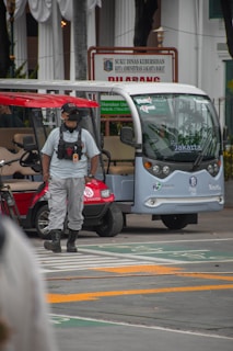 A driver in uniform standing proudly beside a rental vehicle ready for passenger transport.