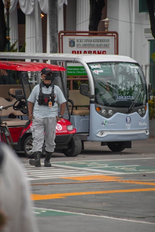 A driver in uniform standing proudly beside a rental vehicle ready for passenger transport.