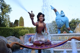 a woman sitting on a fountain with a statue of a man holding a sword