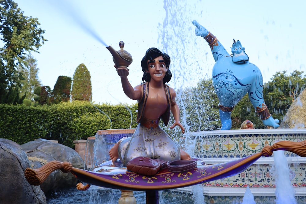 a woman sitting on a fountain with a statue of a man holding a sword