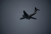 A close-up photo of an airplane in flight with dramatic lighting.