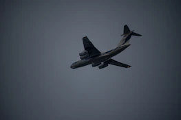 A close-up photo of an airplane in flight with dramatic lighting.