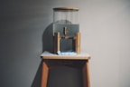 A stylish water dispenser with a clear glass of fresh water beside it.
