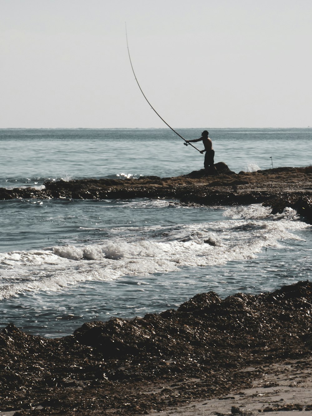 a man fishing on a rocky beach