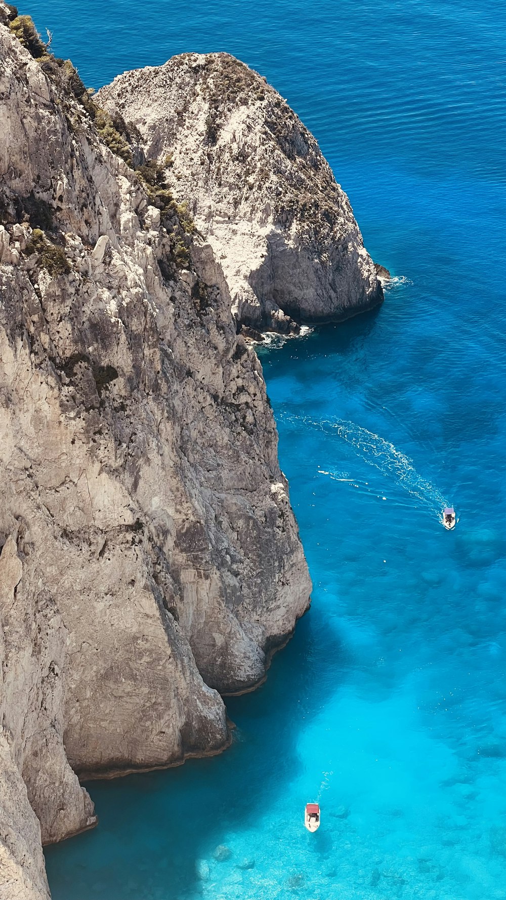 a person in a boat in the water by a rock cliff