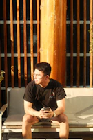 Wide shot of a person sitting on a bench outdoors, the smartwatch catching the last rays of daylight.