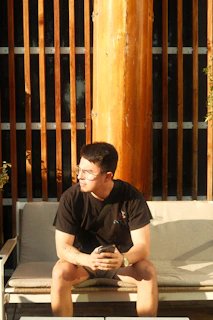 Wide shot of a person sitting on a bench outdoors, the smartwatch catching the last rays of daylight.
