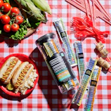 A spread of Diamond Heat sauces and spices arranged on a picnic table at a baseball game.
