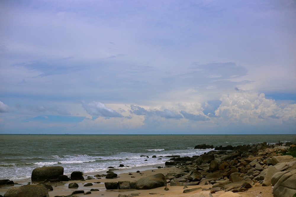 a rocky beach with a body of water in the background