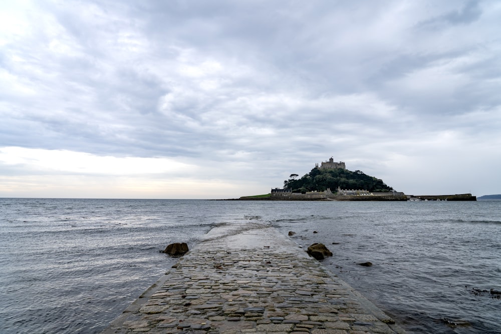 a stone walkway leading to a small island in the ocean