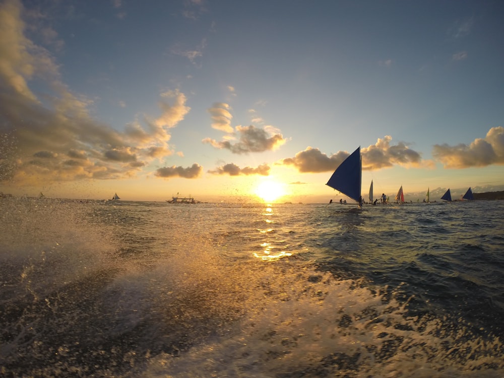 a group of sailboats on the water during sunset