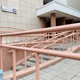 A wheelchair-accessible entryway featuring a threshold ramp and handrails painted deep green.