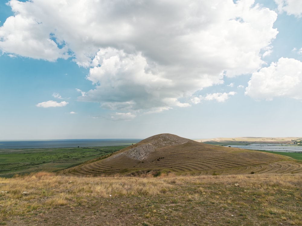 a large hill with a body of water in the background