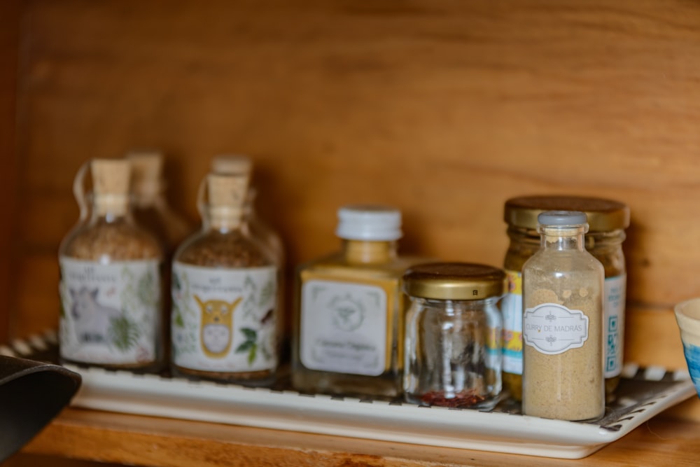 a group of glass jars with white labels on a wooden surface