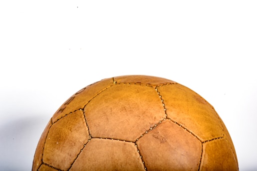 A vintage-style leather soccer ball with visible stitching and pentagonal panels, positioned against a plain white background.