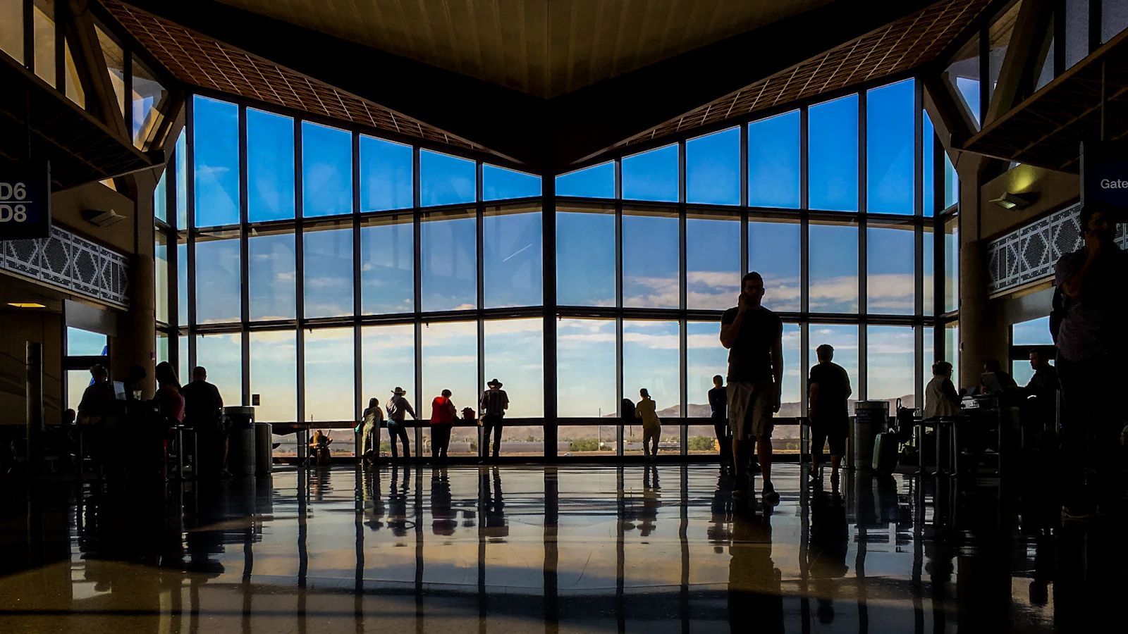 Travellers silhouetted against the tall windows of an airport terminal