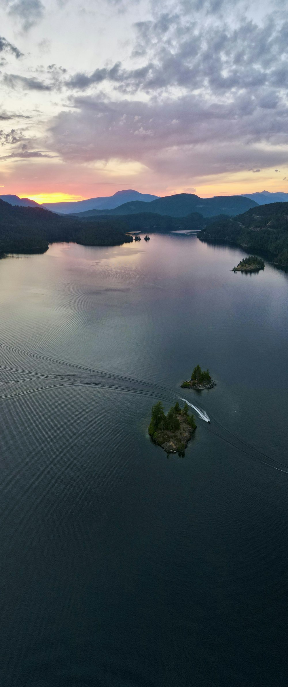 a body of water with trees and mountains in the background