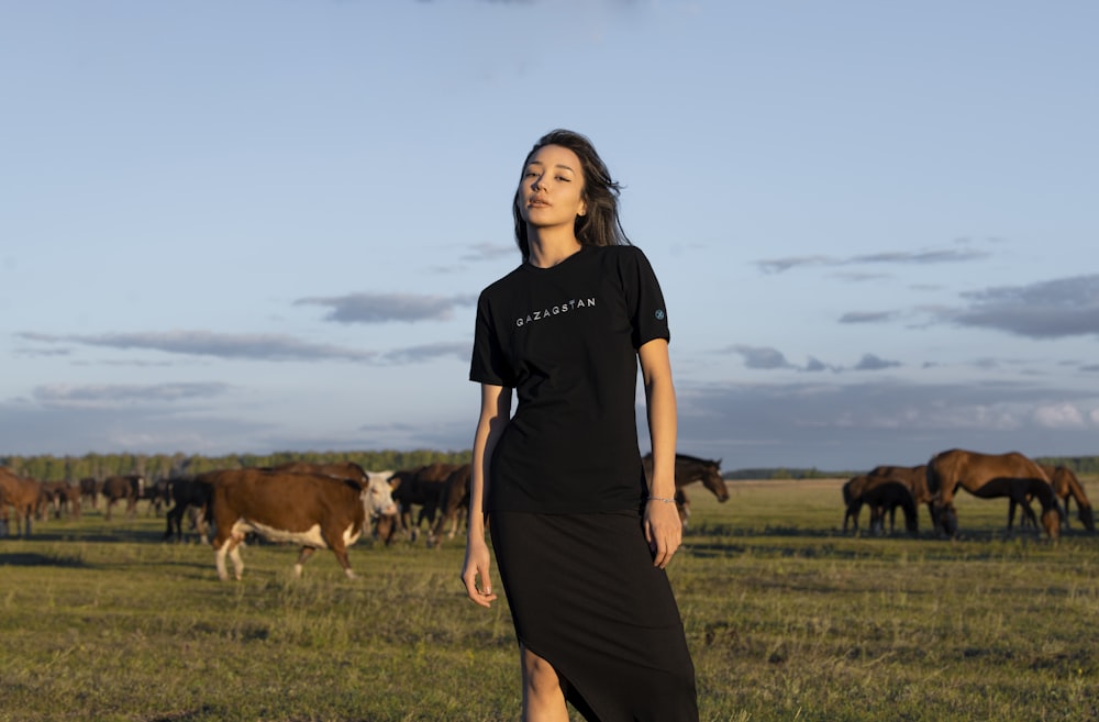 a person standing in a field with cows in the background