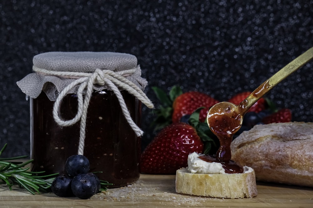 a glass jar with a straw and a couple of strawberries