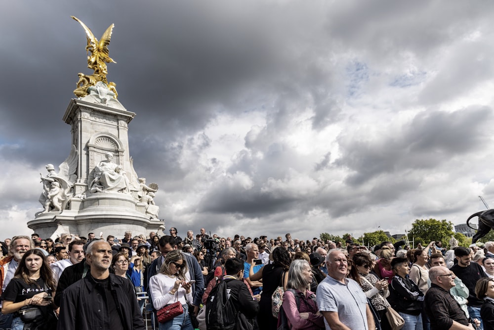 a crowd of people in front of a statue