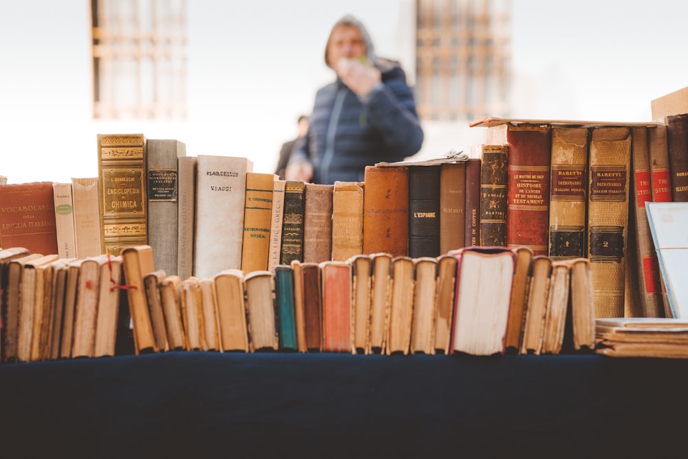 a person standing behind a table with books on it