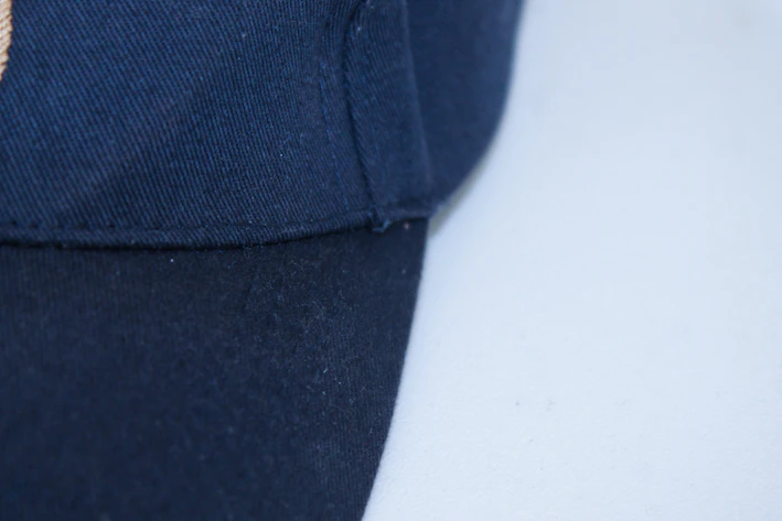 Close-up of a folded black embroidered cap with a minimalist urban background