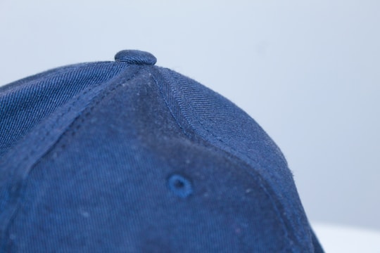 A close-up photo of a classic cap with detailed stitching on a wooden table.