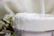 A close-up of a hand scooping creamy body butter from a rustic jar surrounded by fresh herbs.