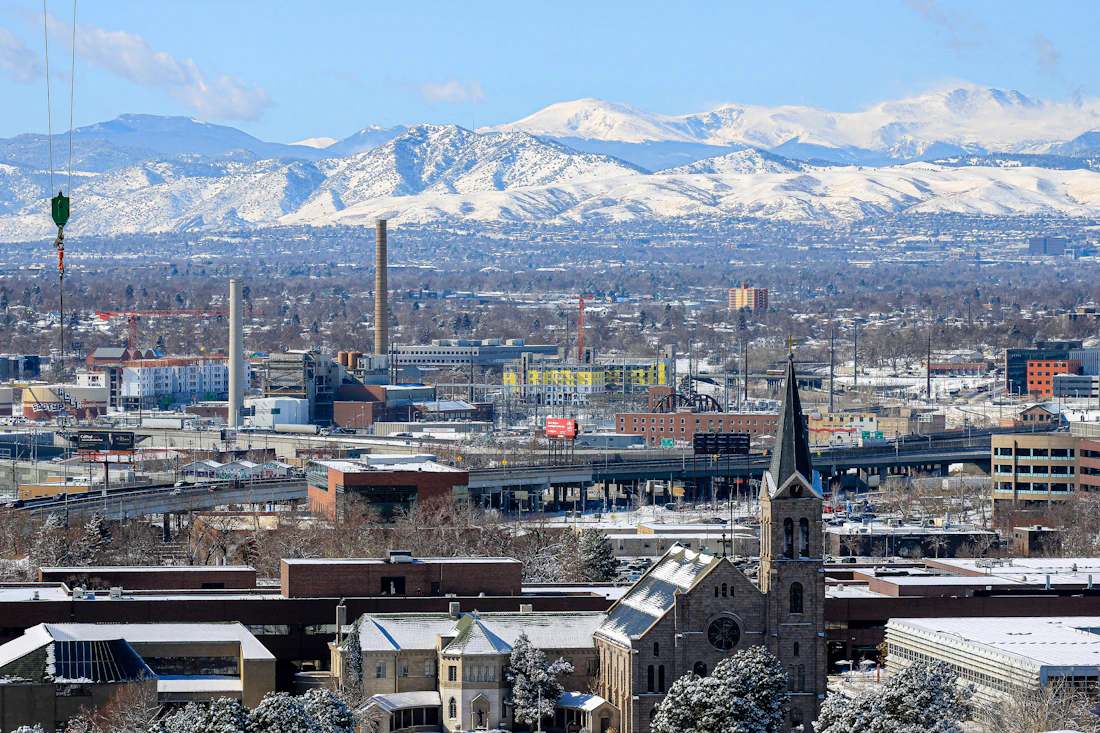 Denver skyline with snow-capped Rocky Mountains behind it