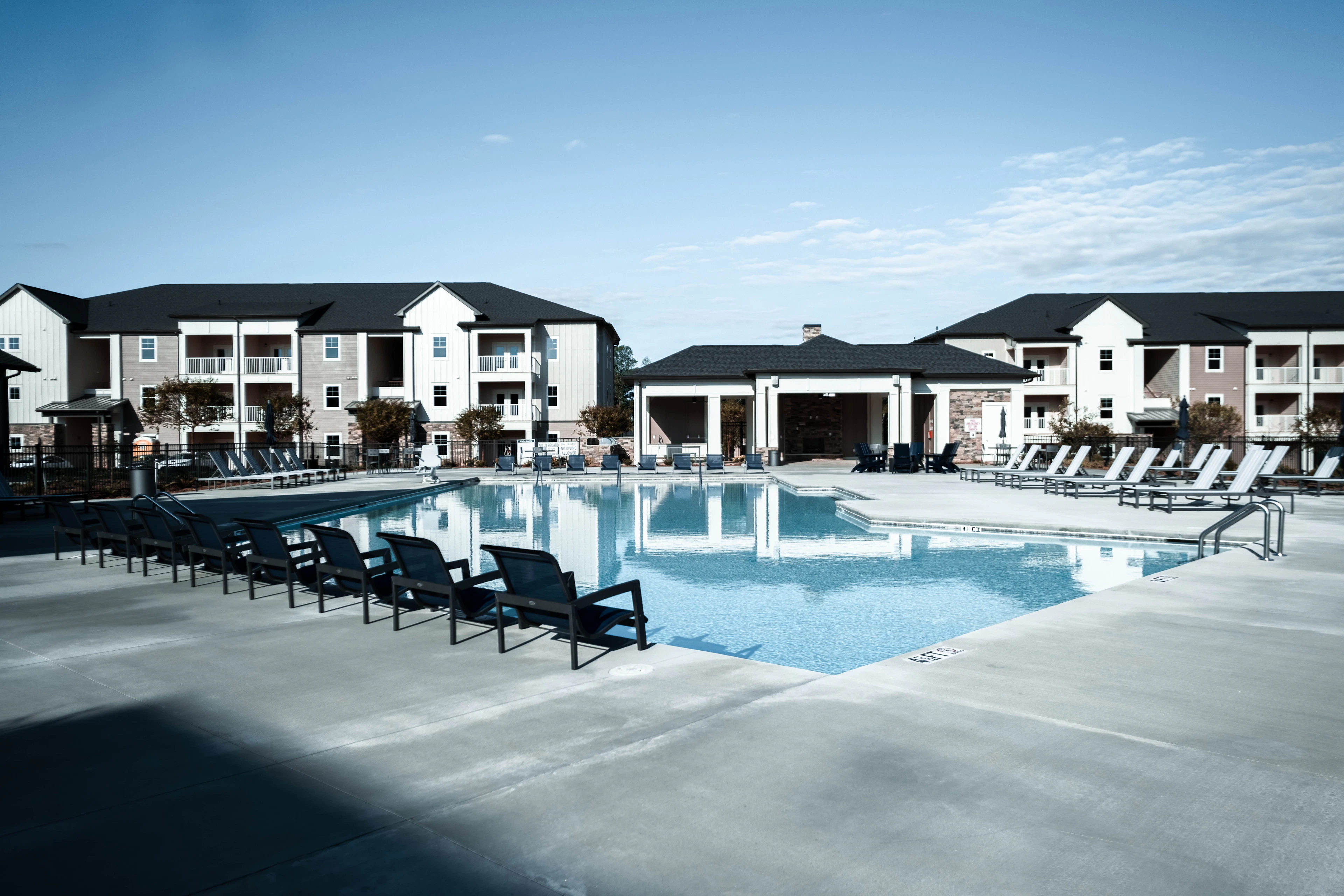 Communal swimming pool with sun loungers beside apartments