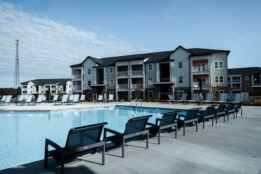 a pool with chairs and tables by it