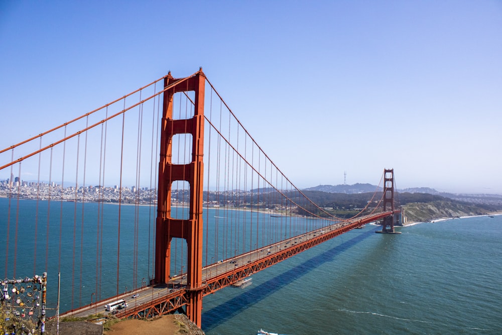 a large red bridge over water with Golden Gate Bridge in the background