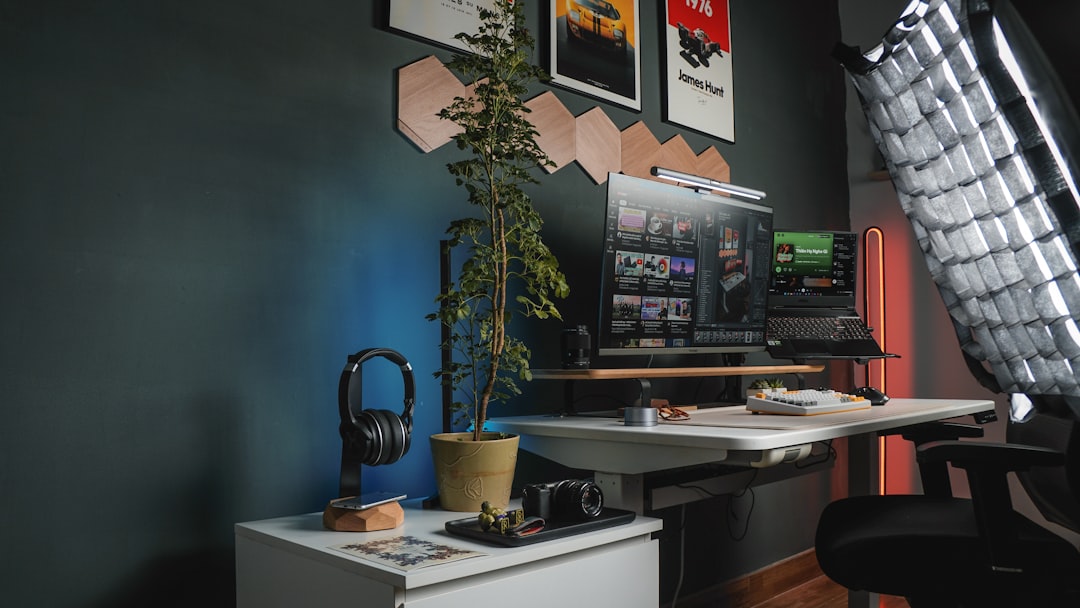 a desk with a computer and a plant on it,