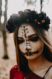 Close-up of the model’s ghostly silver-accented makeup, framed by wild, tangled foliage.