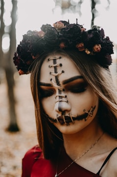 Close-up of the model’s ghostly silver-accented makeup, framed by wild, tangled foliage.