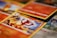 A close-up shot of various Pokémon trading cards laid out, with the focus on a Charmander card. The cards have vibrant and colorful illustrations featuring Pokémon characters and associated game stats.