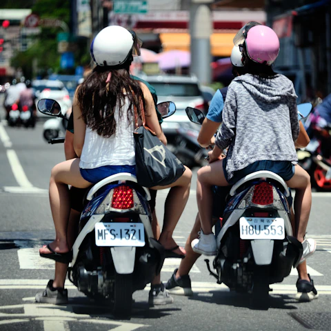 a couple of women ride on a scooter