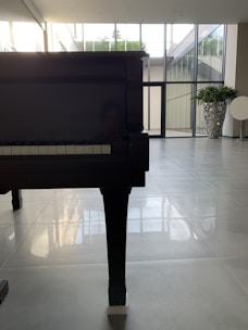 A compact upright piano standing elegantly in a bright, sunlit room.