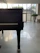 A beautifully polished grand piano set up in a sunlit wedding venue with floral decorations.