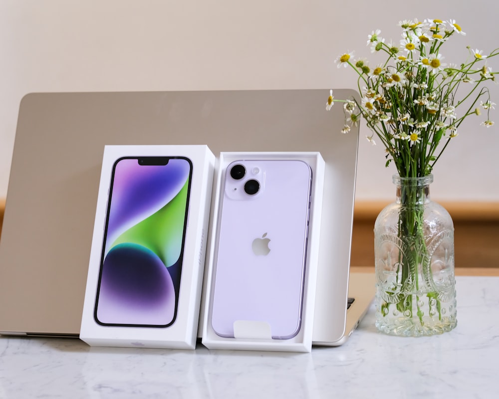 a group of cell phones in a vase next to a vase of flowers