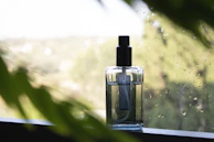 An elegant mist spray bottle surrounded by fresh citrus fruits and green leaves.
