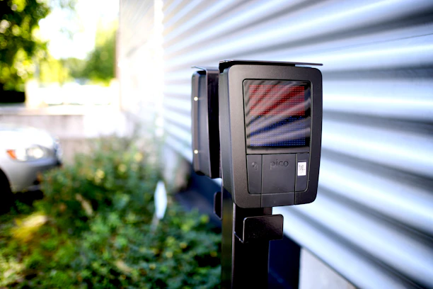 A technician installing a solar-powered wireless parking barrier at a residential parking lot.